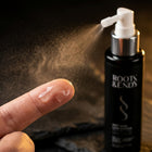 Light watery lotion on a fingertip beside the Roots & Ends spray